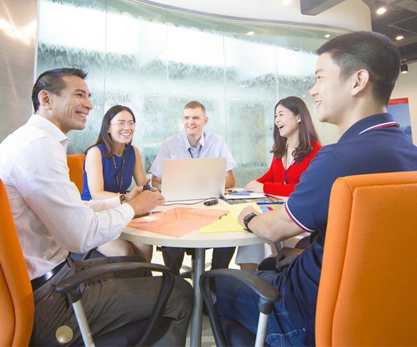 Mitarbeitende sitzen in einem Konferenzraum um einen Tisch.