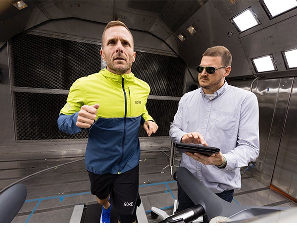Two people in the environmental chamber. One running on a treadmill with a GORE-TEX Garment on and the other recording findings.